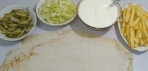 In order to wrap the shawarma properly, bring the following ingredients (garlic garlic - pickled cucumber - lettuce slices) and tortilla bread and place them on a large table